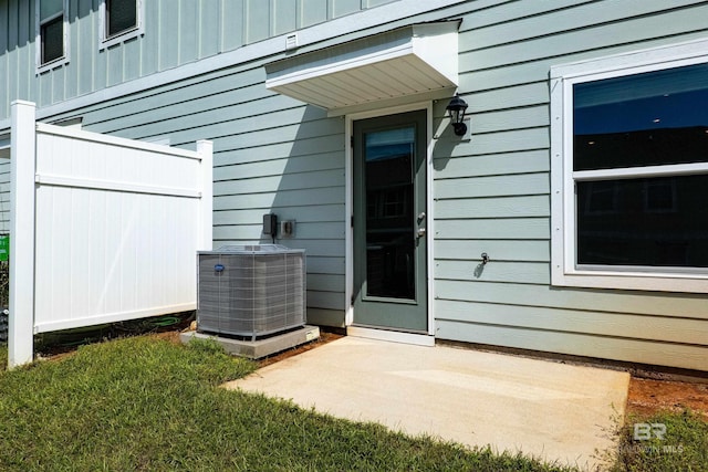 view of exterior entry featuring a yard and central air condition unit