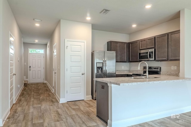 kitchen with sink, kitchen peninsula, light hardwood / wood-style flooring, stainless steel appliances, and dark brown cabinetry