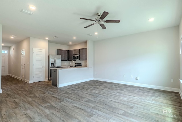 kitchen featuring ceiling fan, dark brown cabinetry, kitchen peninsula, wood-type flooring, and stainless steel appliances