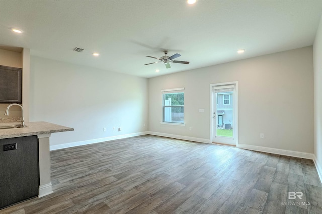 unfurnished living room with ceiling fan, sink, and dark wood-type flooring