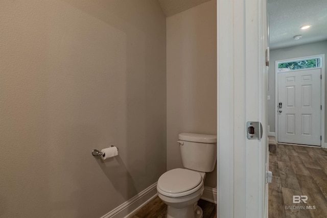 bathroom featuring wood-type flooring, a textured ceiling, and toilet