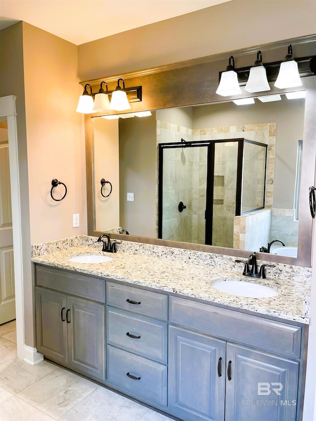 bathroom with a stall shower, double vanity, and a sink
