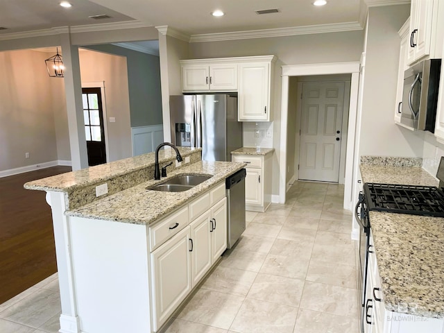 kitchen with stainless steel appliances, an island with sink, crown molding, and a sink