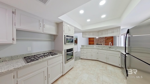 kitchen featuring light stone countertops, sink, appliances with stainless steel finishes, and white cabinetry