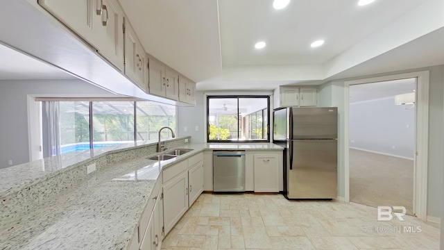 kitchen featuring light stone countertops, appliances with stainless steel finishes, sink, and light colored carpet