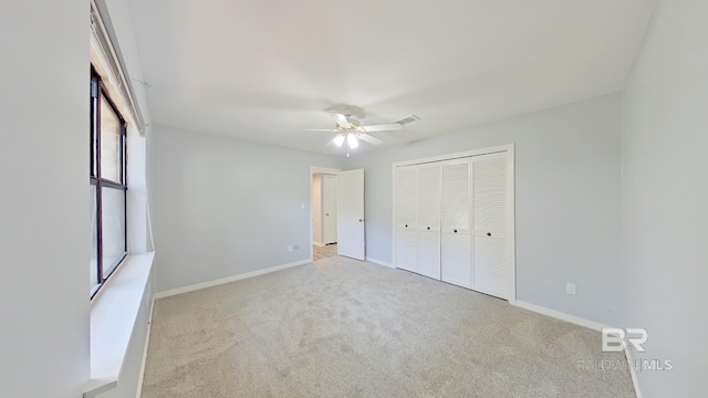 unfurnished bedroom featuring light carpet, a closet, and ceiling fan