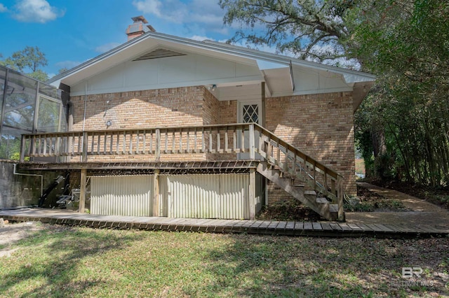 back of property featuring a deck and a lawn