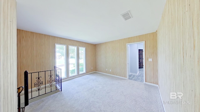 unfurnished room featuring carpet floors and wooden walls