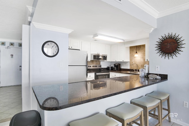 kitchen with tasteful backsplash, crown molding, appliances with stainless steel finishes, a peninsula, and a sink