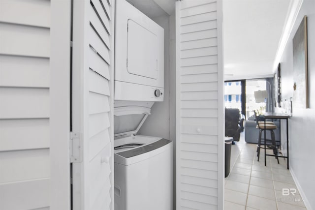 washroom with light tile patterned floors, laundry area, baseboards, and stacked washer and dryer