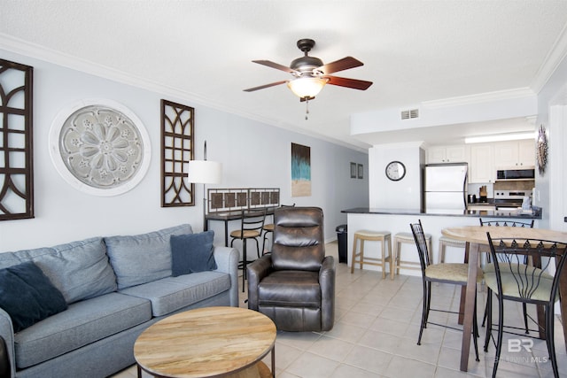 living room with visible vents, ornamental molding, a textured ceiling, light tile patterned floors, and ceiling fan