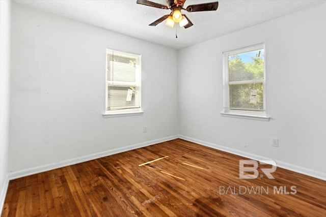 spare room with plenty of natural light, baseboards, and wood finished floors