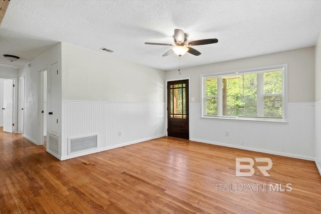 spare room featuring visible vents, a ceiling fan, and wood finished floors