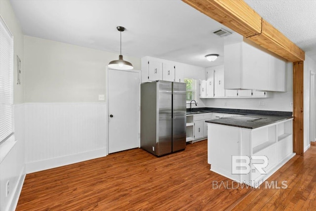kitchen with visible vents, freestanding refrigerator, dark countertops, white cabinets, and a sink