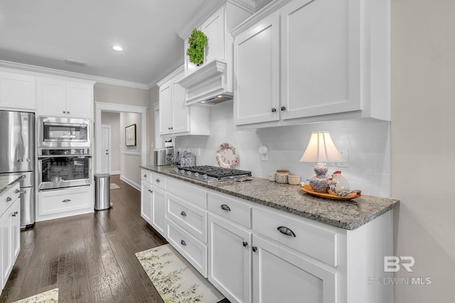 kitchen featuring appliances with stainless steel finishes, white cabinets, backsplash, and light stone counters
