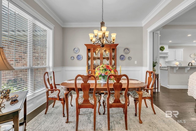 dining room with an inviting chandelier, ornamental molding, dark wood finished floors, and a wainscoted wall