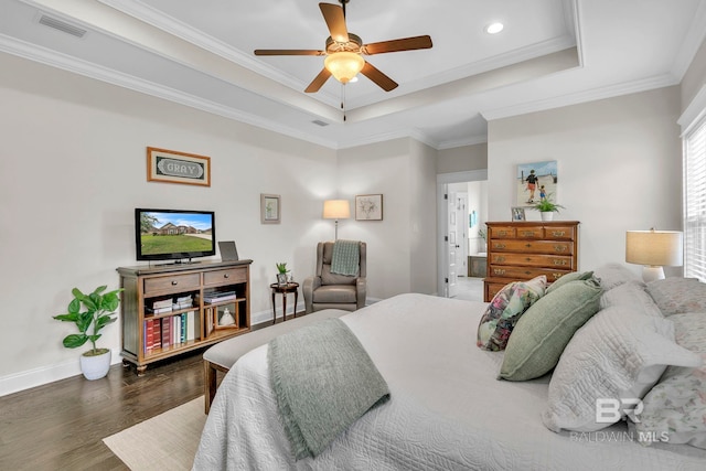 bedroom featuring visible vents, crown molding, wood finished floors, baseboards, and a tray ceiling