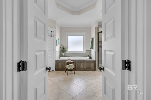 full bathroom with a raised ceiling, ornamental molding, and a bath