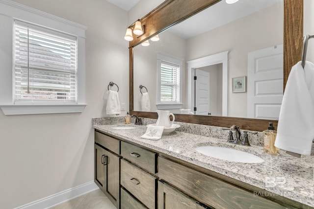 bathroom featuring a sink, baseboards, tile patterned flooring, and double vanity