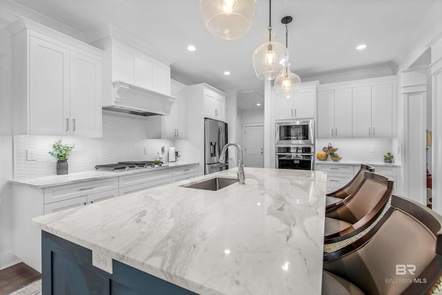 kitchen featuring sink, a kitchen bar, stainless steel appliances, decorative light fixtures, and a spacious island