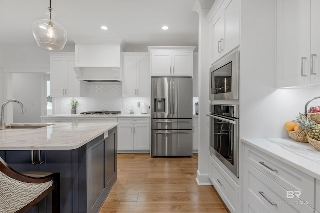 kitchen featuring white cabinets, sink, decorative light fixtures, stainless steel appliances, and light hardwood / wood-style floors