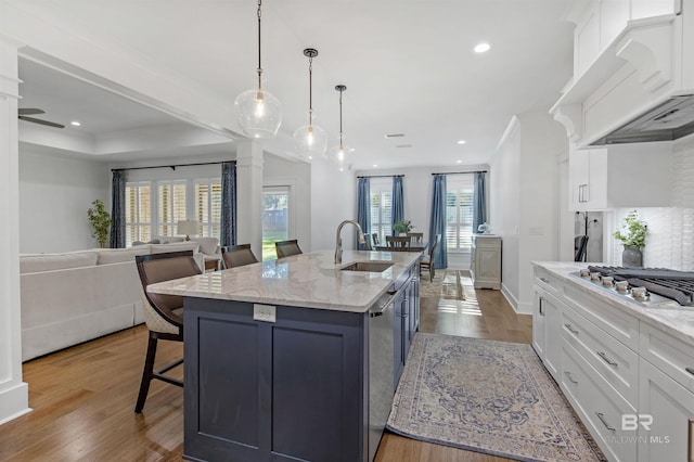 kitchen with custom exhaust hood, plenty of natural light, sink, and white cabinetry