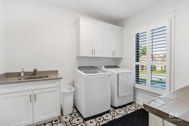 laundry area with cabinets, washing machine and dryer, light tile patterned floors, and sink