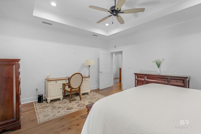 bedroom featuring a tray ceiling, ceiling fan, and hardwood / wood-style floors