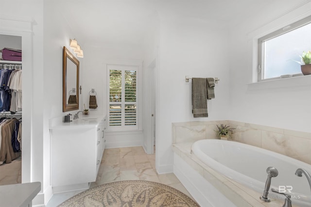 bathroom with a relaxing tiled tub and vanity