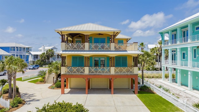 1219 Parasol Pl, Perdido Key, FL 32507 - coastal inspired home featuring a balcony, a standing seam roof, an attached garage, metal roof, and concrete driveway