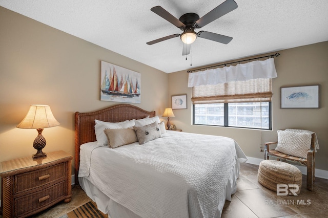 bedroom featuring ceiling fan, tile patterned floors, and a textured ceiling