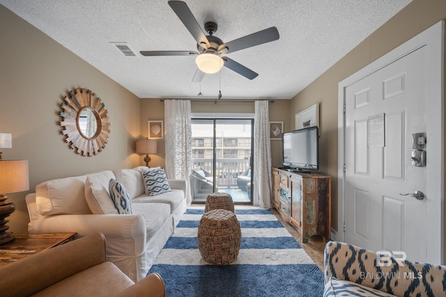 living room with ceiling fan and a textured ceiling