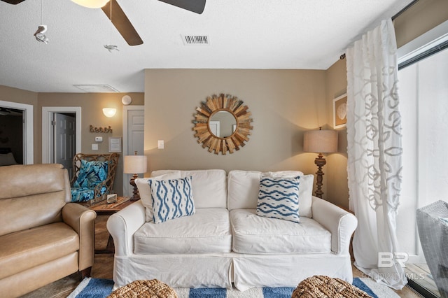 living room with a textured ceiling, a wealth of natural light, and ceiling fan