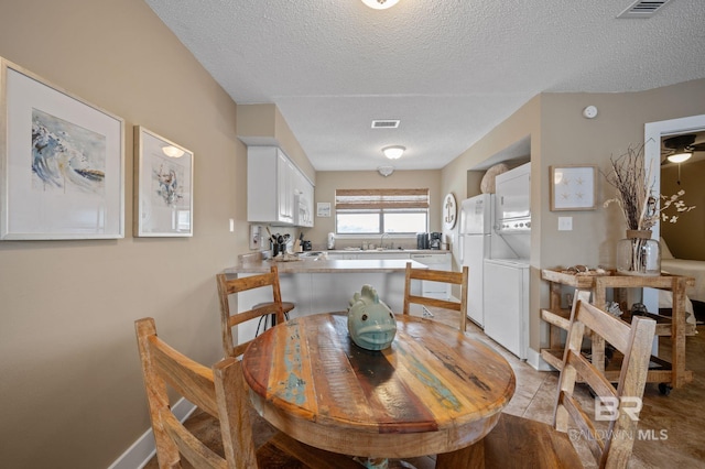 dining space featuring sink, stacked washer and clothes dryer, and a textured ceiling