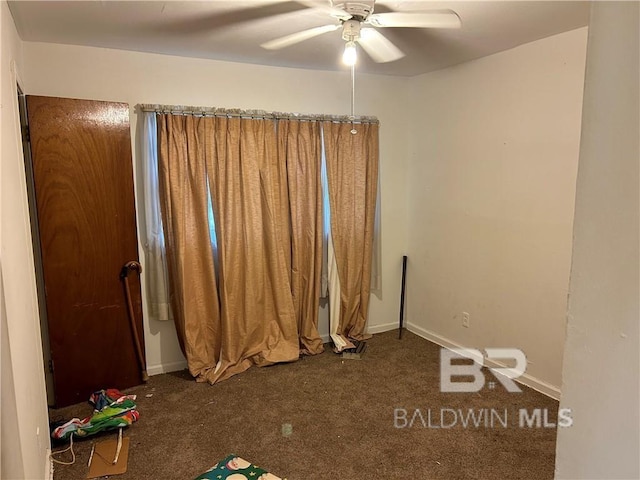 interior space with ceiling fan and dark carpet