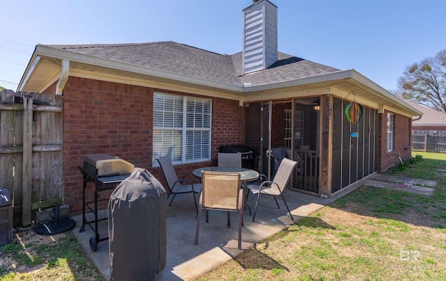 view of patio featuring a sunroom, outdoor dining space, and fence