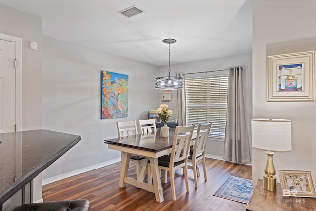 dining room with dark wood finished floors, visible vents, and baseboards