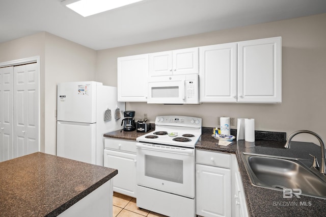 kitchen with dark countertops, white appliances, white cabinets, and a sink