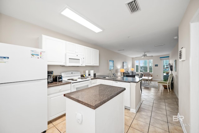 kitchen with dark countertops, visible vents, a kitchen island, white appliances, and a peninsula