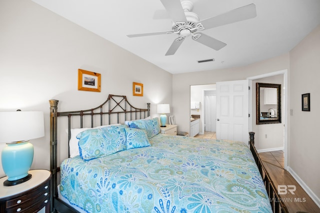 bedroom featuring a ceiling fan, visible vents, ensuite bath, and baseboards