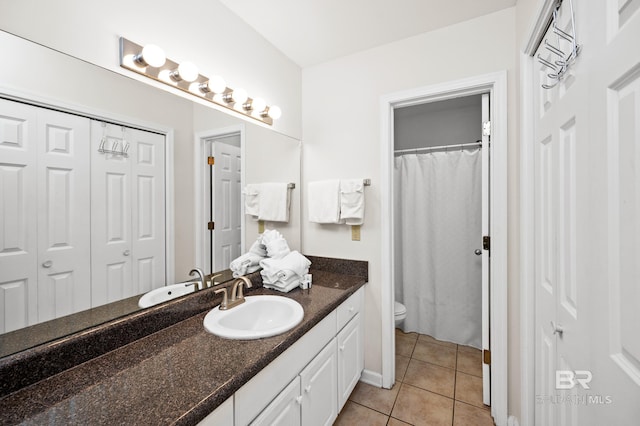 bathroom featuring toilet, vanity, a closet, and tile patterned floors