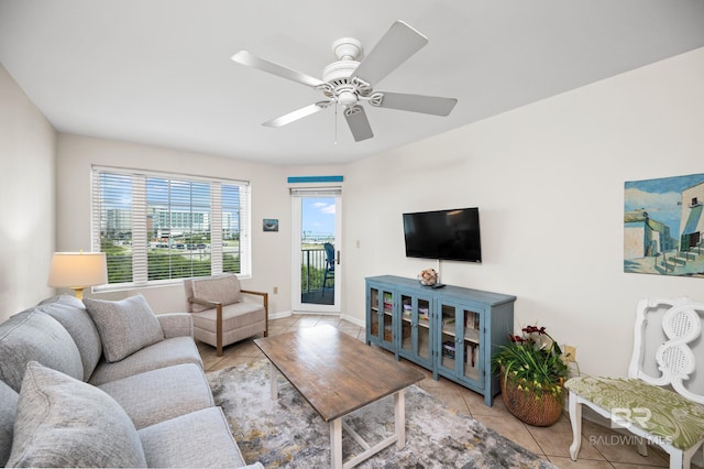 living area with ceiling fan, baseboards, and light tile patterned floors