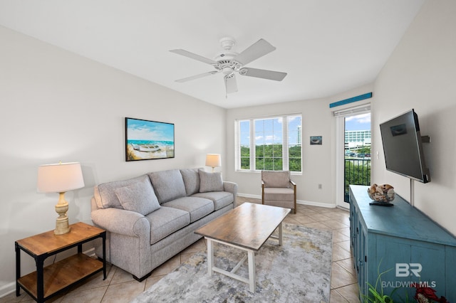 living area featuring light tile patterned floors, a ceiling fan, and baseboards