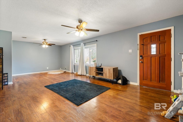 entrance foyer featuring ceiling fan, baseboards, a textured ceiling, and wood finished floors