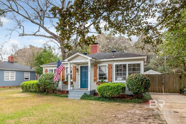 bungalow-style house with fence, roof with shingles, a chimney, a front lawn, and crawl space