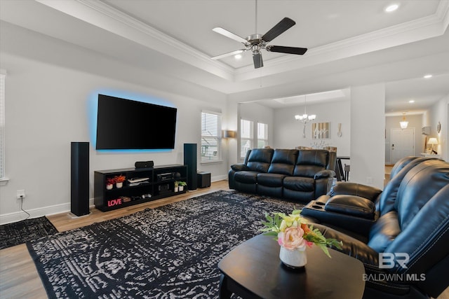 living room featuring ceiling fan with notable chandelier, a tray ceiling, hardwood / wood-style flooring, and crown molding