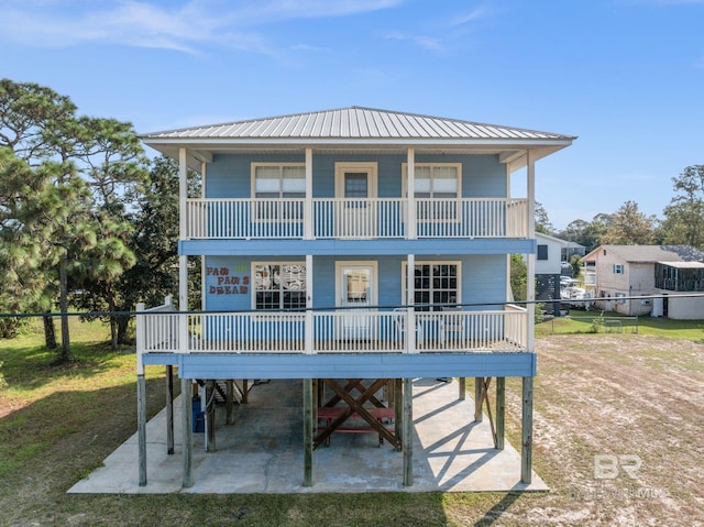 5584 Pensacola Ave, Orange Beach, AL 36561 - view of front facade featuring metal roof, a front yard, a carport, fence, and a balcony