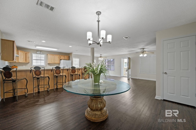 5584 Pensacola Ave, Orange Beach, AL 36561 - dining area featuring ceiling fan with notable chandelier, dark wood-style flooring, a textured ceiling, and visible vents