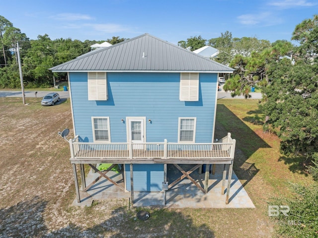 5584 Pensacola Ave, Orange Beach, AL 36561 - rear view of house featuring a yard, a patio, a wooden deck, and metal roof