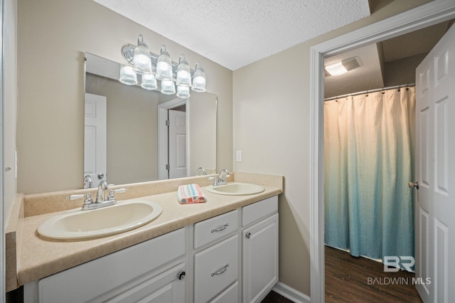 5584 Pensacola Ave, Orange Beach, AL 36561 - full bath featuring double vanity, a sink, a textured ceiling, and wood finished floors